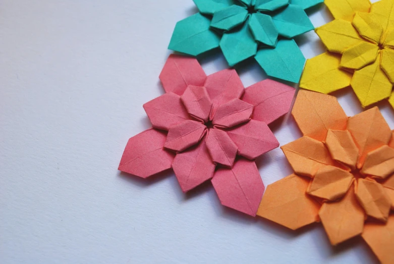 four colorful paper flowers with one flower facing the right