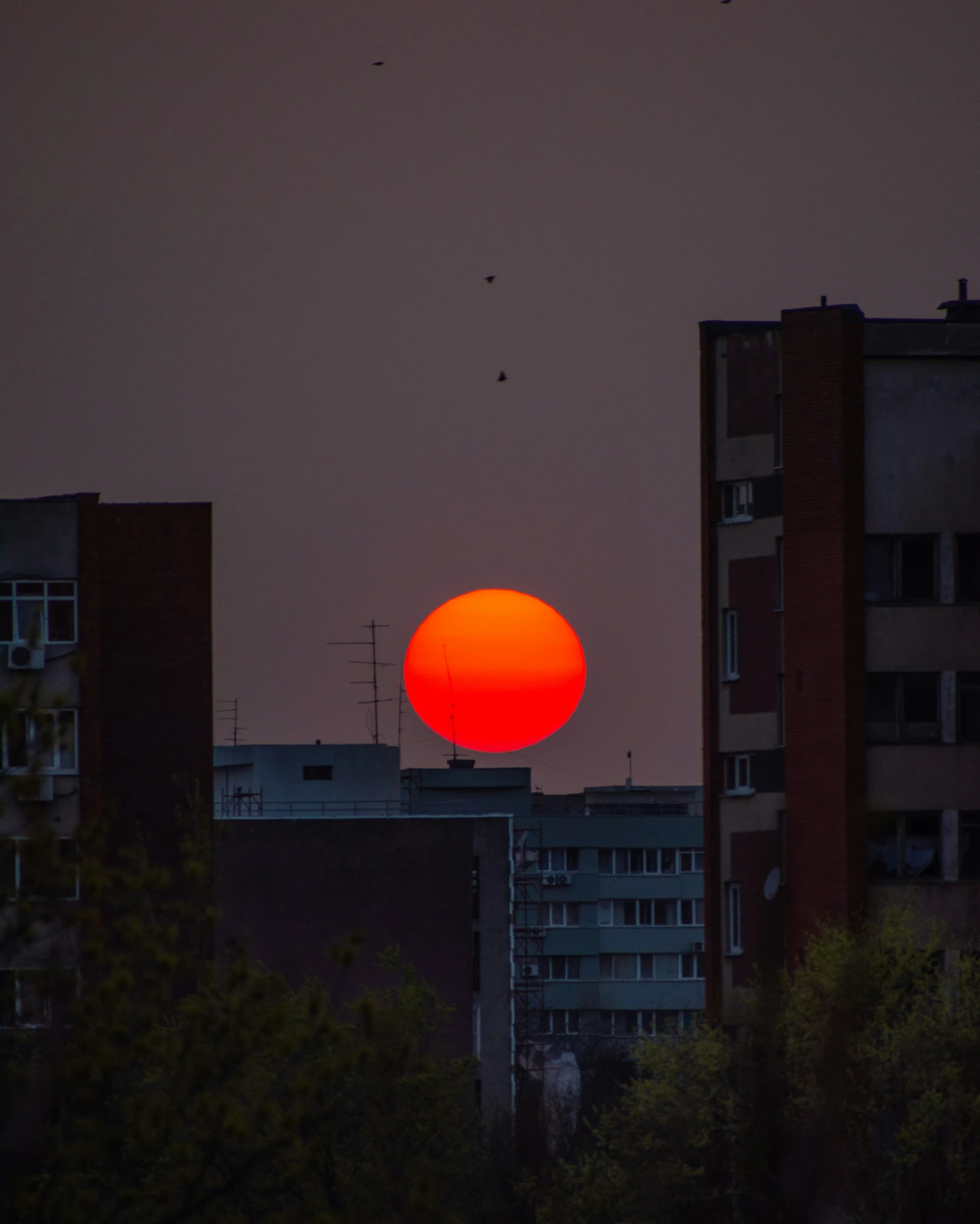 the sun is setting behind several tall buildings