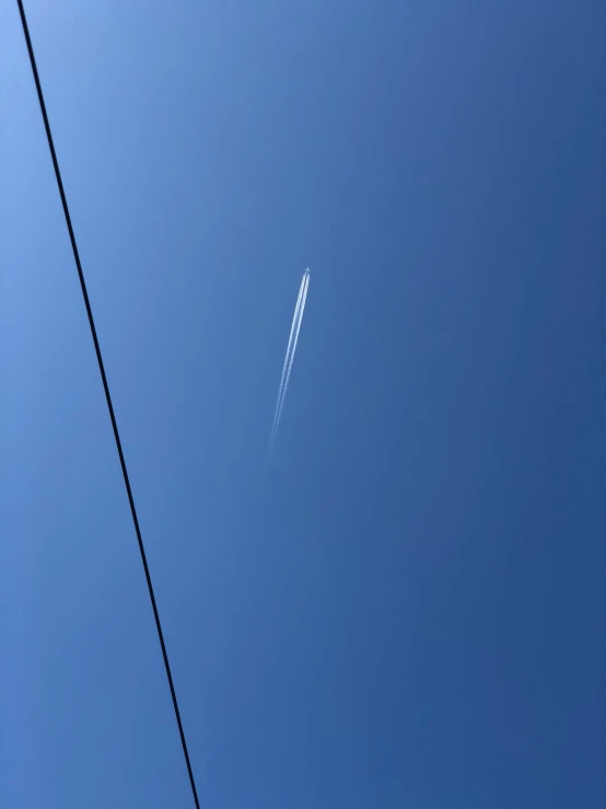 an airplane flies high in the air while power lines pass by