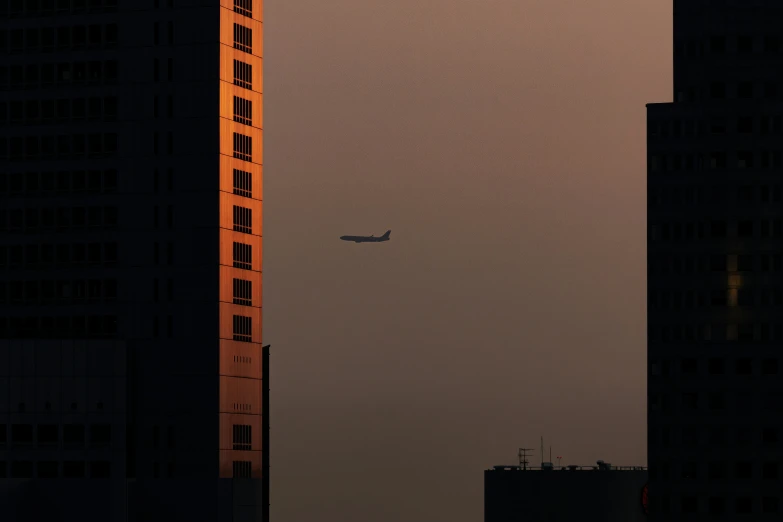 a large passenger jet flying above tall buildings