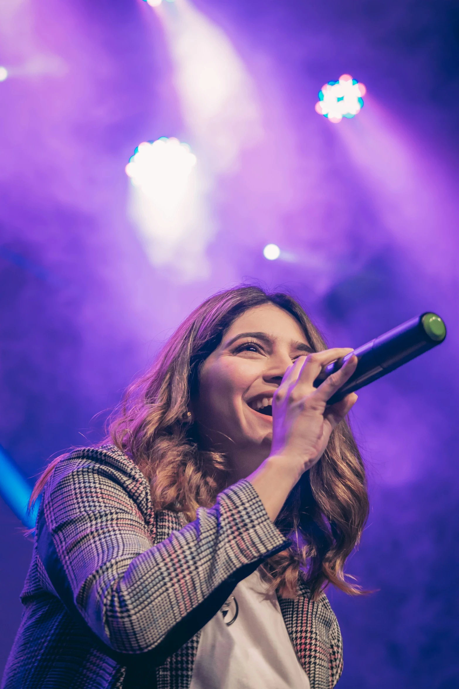 woman singing on stage, she has microphone in her hand