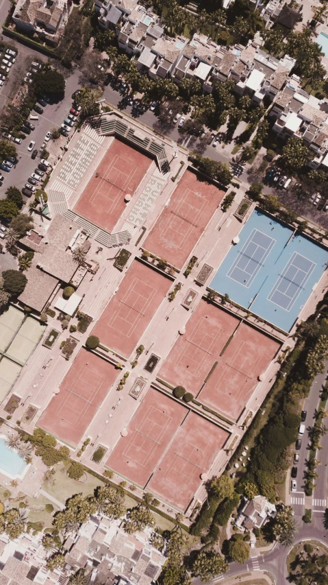 an aerial view of a tennis court with red clay and concrete