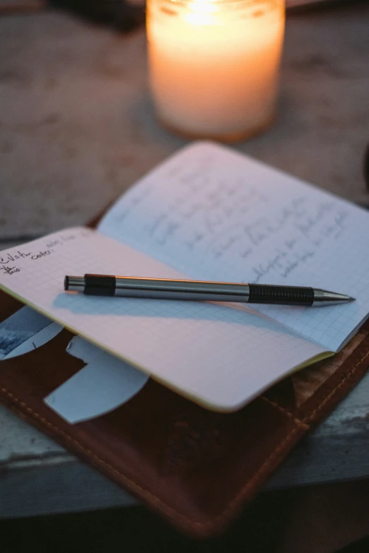 a notepad sitting next to a candle