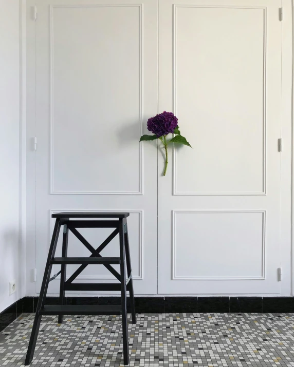 a flower is on a white wall and there are black chairs with a purple flower