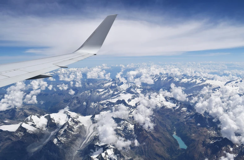 an airplane is flying over the mountains and clouds