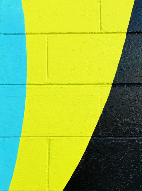 a painted blue yellow and black wall next to a brick