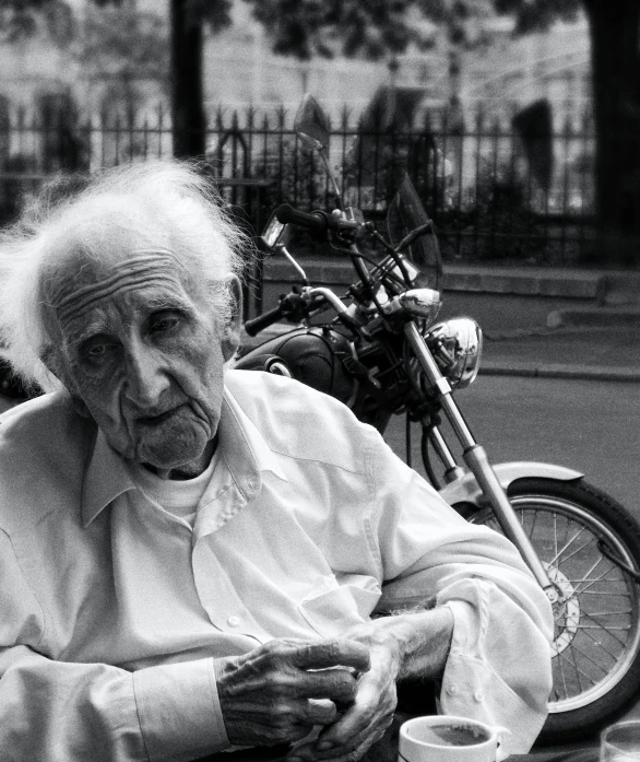 a black and white image of an old lady by her bike