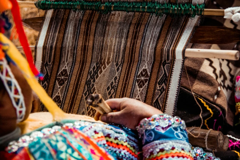 a person sitting in front of a colorful rug