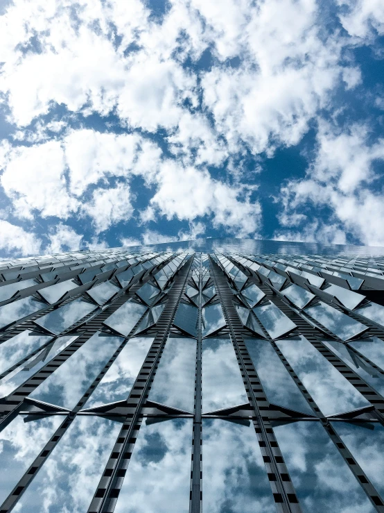 the view looking up at the sky and clouds from the inside of the glass building