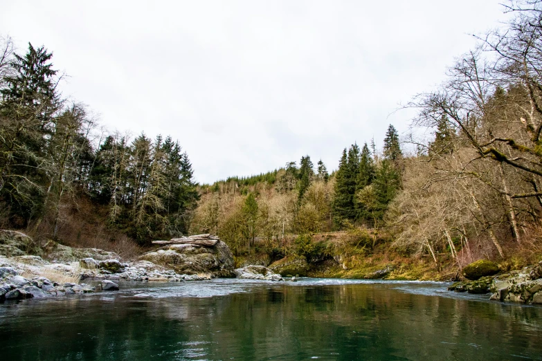 the river is calm and quiet, with snow on the ground