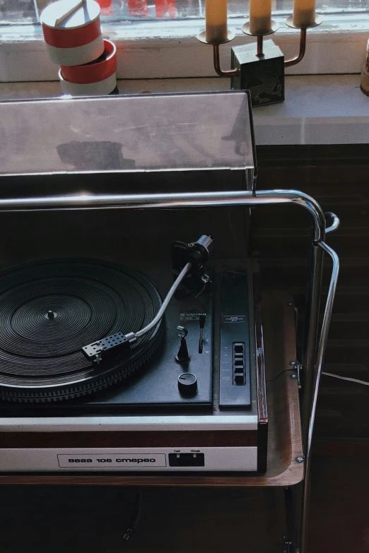 a turntable sitting next to a window on top of a table