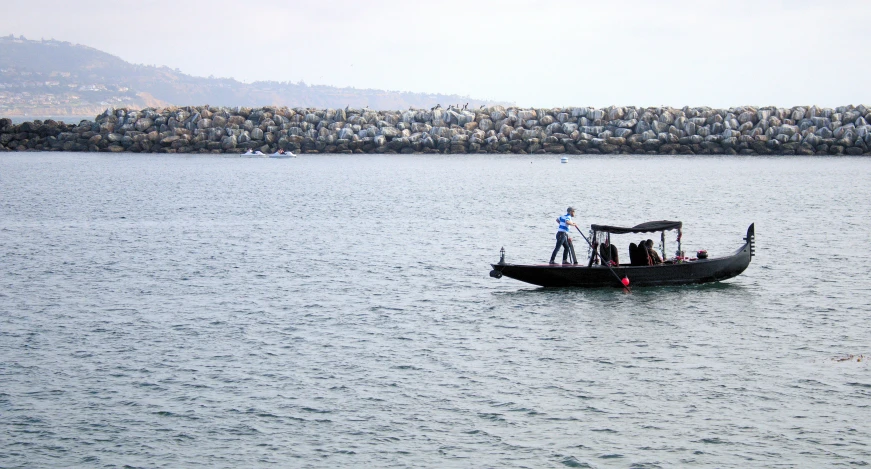 a black boat with people on it in a lake