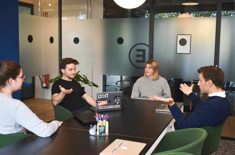 five people sit around a table and talk