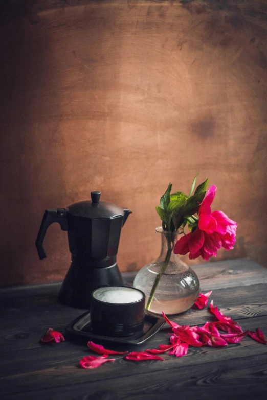 flowers sit in a glass vase next to a coffee pot