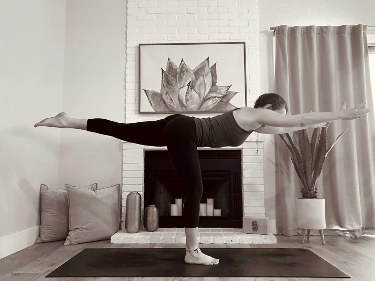 a woman stands on a mat and does yoga in a living room