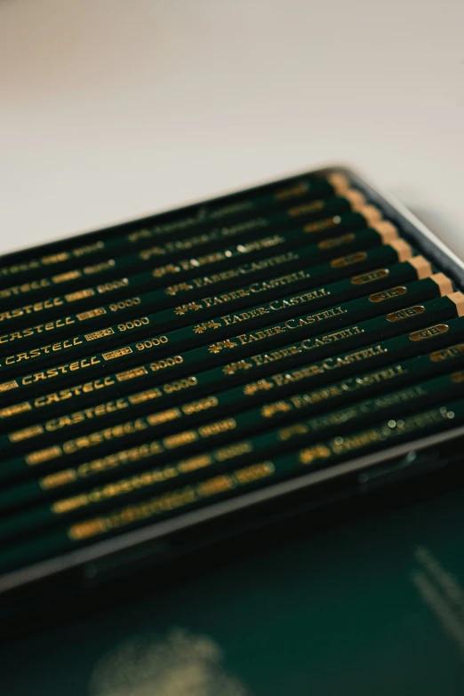 some black and gold colored pencils are laying on a desk