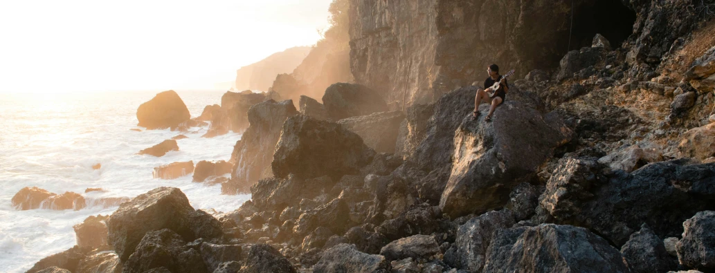 two people climbing on rocky rocks along the beach