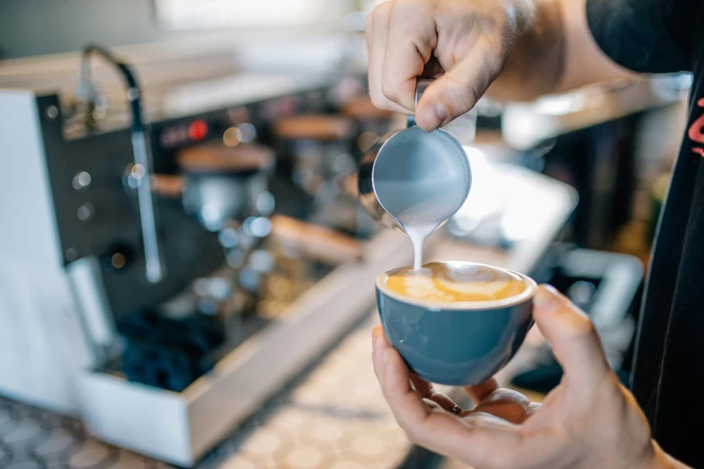 a baristale pours some drink into a cup