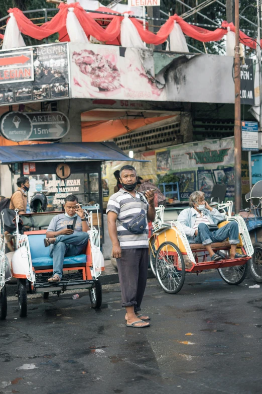 some people are driving some carts and bicycles on the street