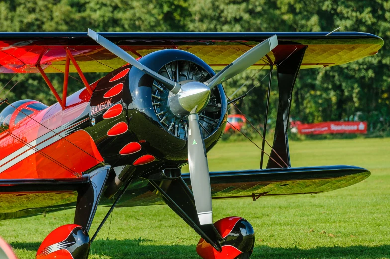 an older red and black plane sitting on grass