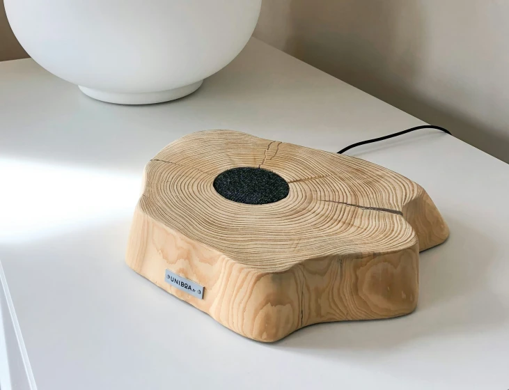 a clock sitting on a white table near a vase