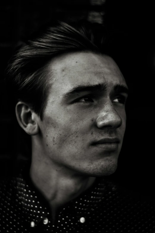 a man standing in front of a brick wall with a serious look on his face