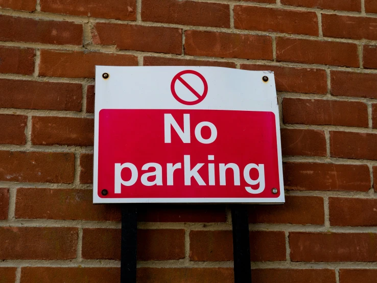 a no parking sign is posted on a wall