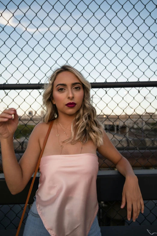 a young woman is posing for a picture behind a fence