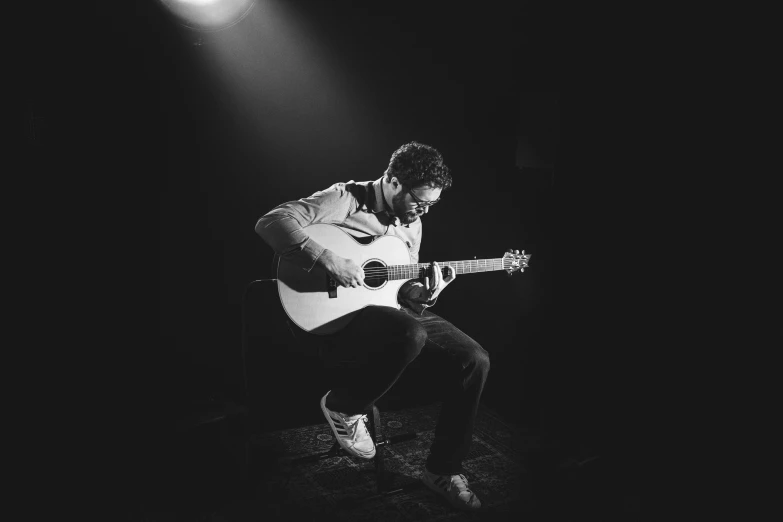 a person playing an acoustic guitar in a dark room