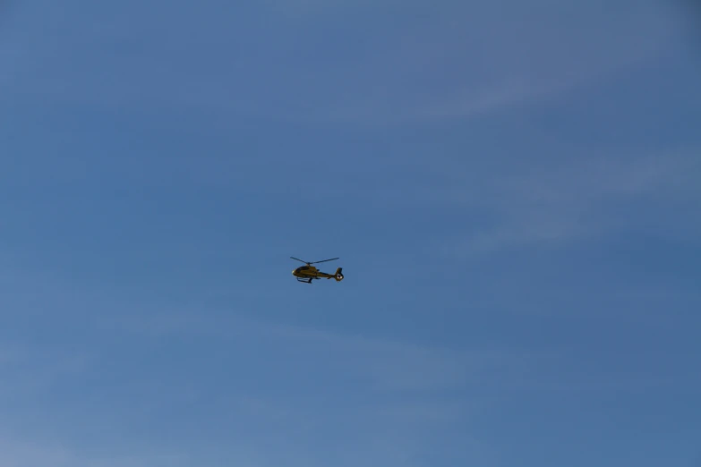 a helicopter flying through the blue sky over a building