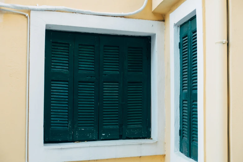 green shutters of a building near a wall