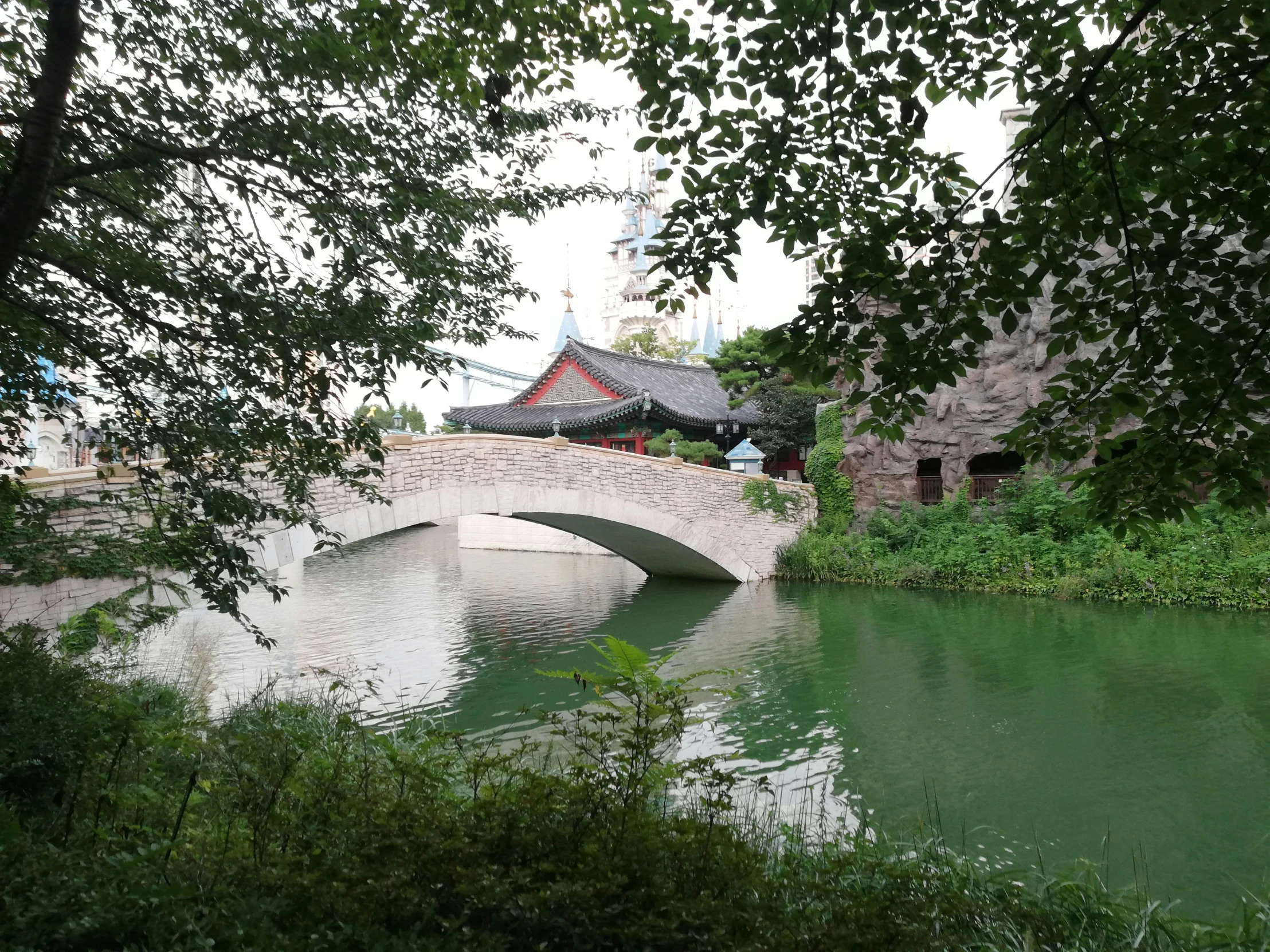 a bridge over a small lake with a few people walking by