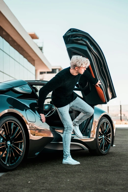 man unloading and changing his gear on top of a sports car