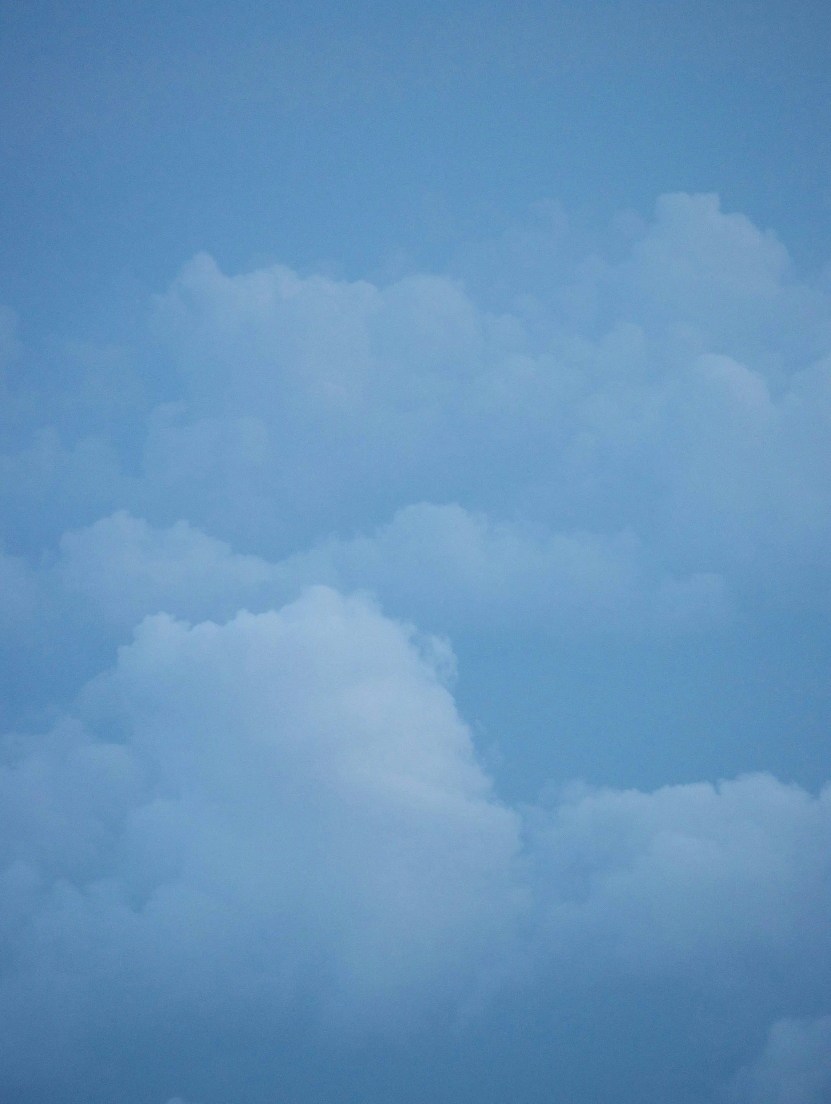 a jet flies high above the clouds in a blue sky