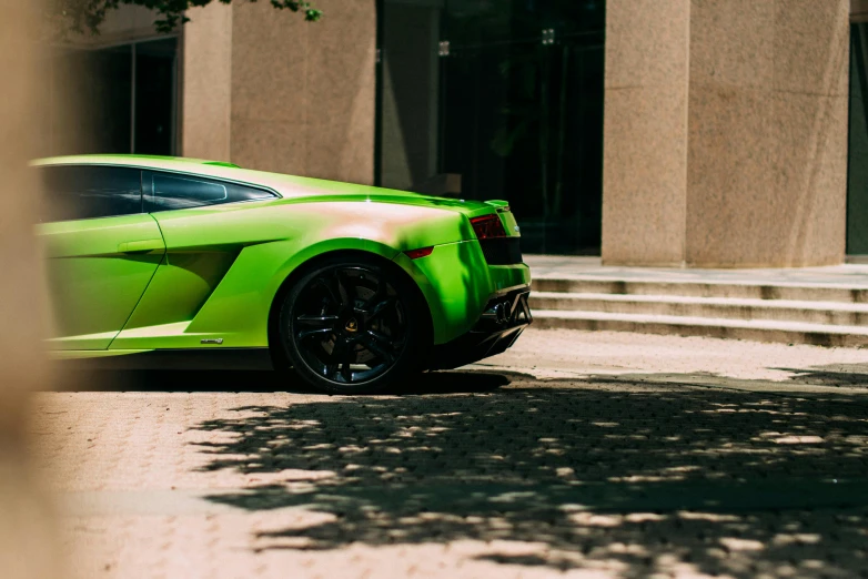 a green sport car on the street near stairs