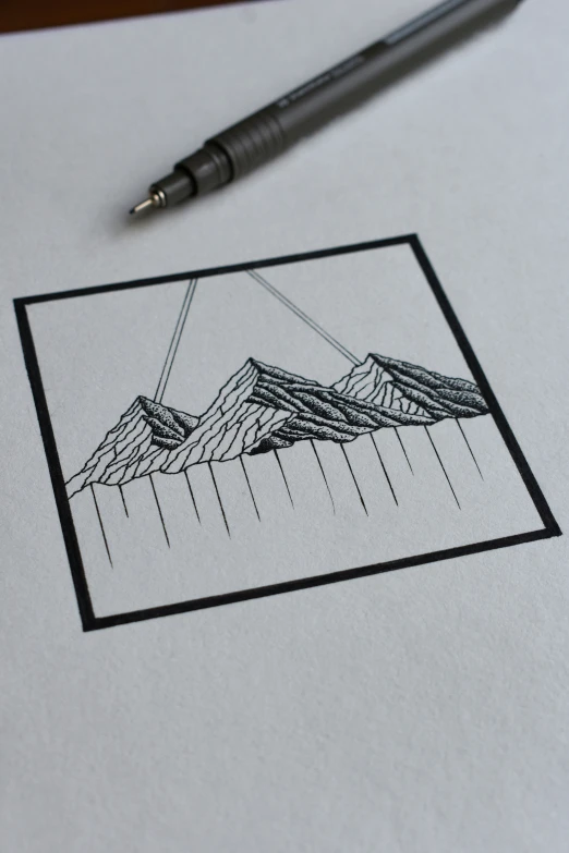 pen and drawing on top of paper with mountains