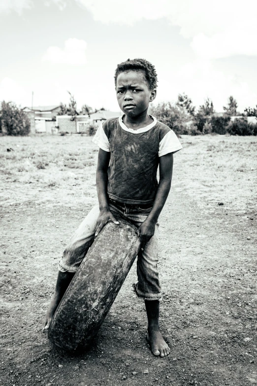 the boy holds a wooden skateboard near his face