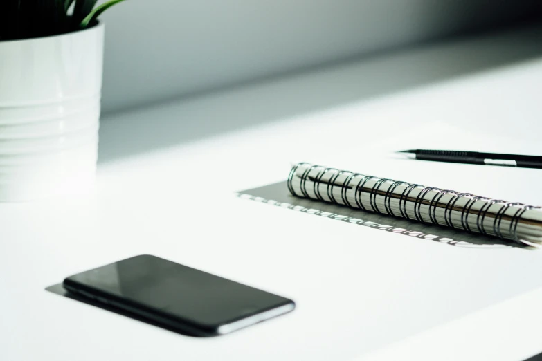 a table that has a phone and a pen on it