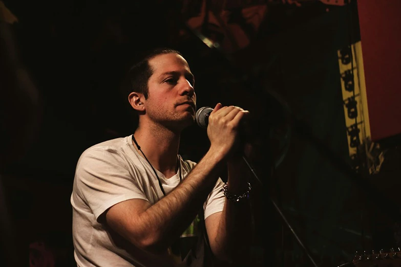 a man that is holding a guitar up to his face