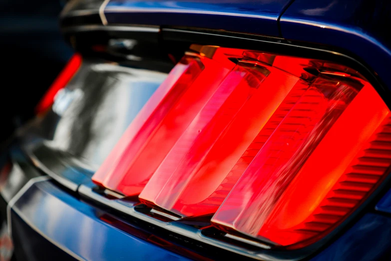 the trunk of a blue car with red lights on