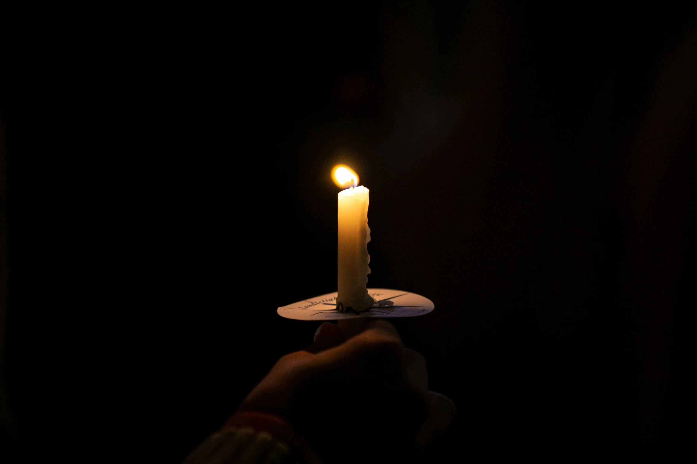 a single lit candle on a small wooden table