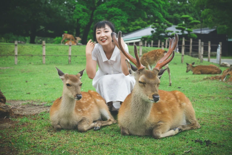 a woman posing with some deer and two deer