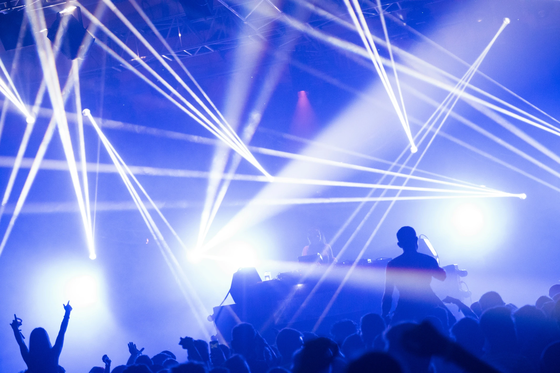 a dj performing in front of white and blue rays