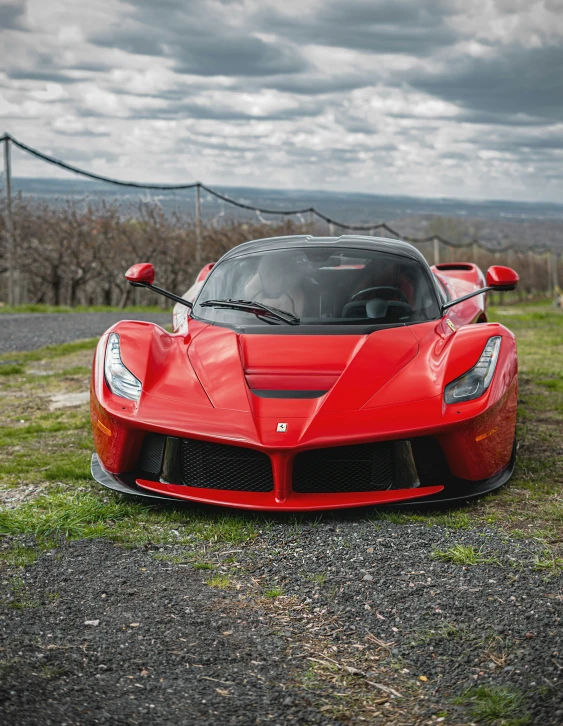 a red sports car is on a gravel road