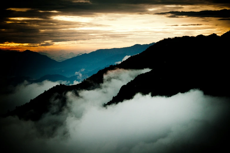 some mountains covered in dark clouds under a dark sky