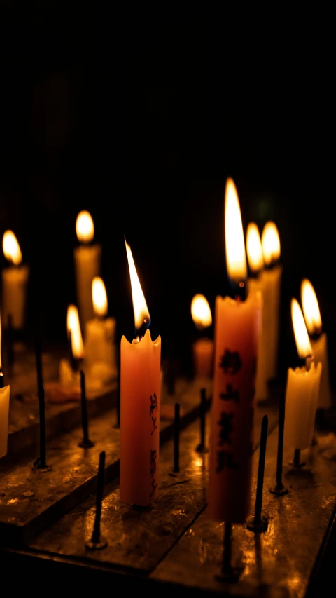 a close up of many lit candles in a dark place