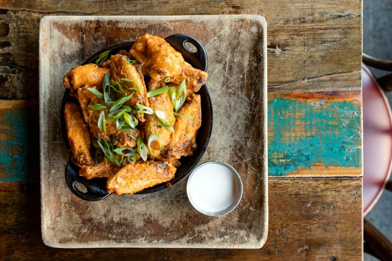 some food is in a black plate on a wooden table