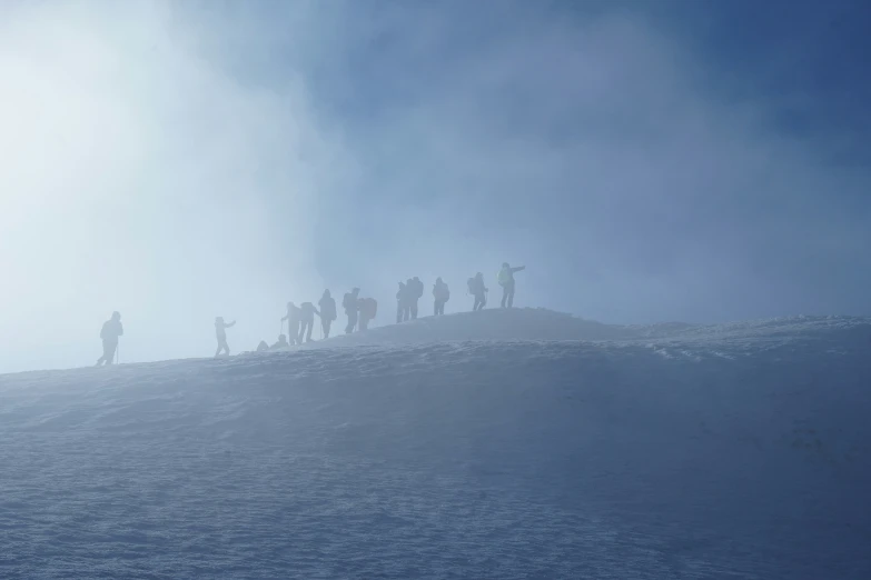 the shadow is cast on a foggy sky as people are gathered on the side of a hill