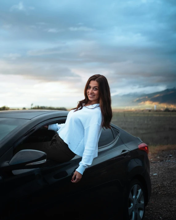 a beautiful woman in white shirt leaning out the car window