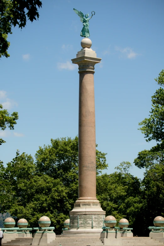 a tall pillar with a statue near trees